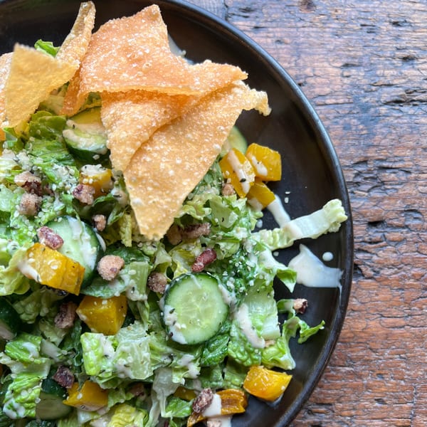 A healthy Bandaloop salad with lettuce, cucumbers, yellow bell peppers, and crispy wonton strips.